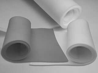 three rolls of thin and thick white and gray sponge foam material

