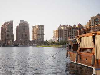 Traditional boat, modern towers, calm water.