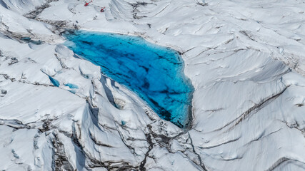 aerial landscape view of a massive Glacier with rugged surface, with two red Helicopters on surface...