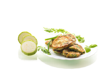 appetizing zucchini pancakes with green onions in a plate on a white background