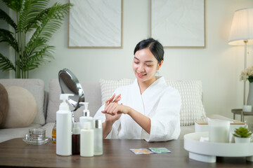 Asian woman applying moisturizing cream during personal skincare routine. Wellness and self care at...
