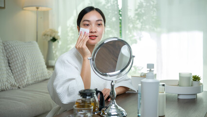 Beautiful Asian woman cleansing her face, using a cotton pad and gentle toner © wattana