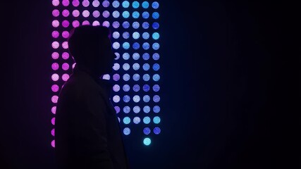 Silhouette of a person against a wall of vibrant, colorful LED lights - Powered by Adobe