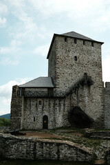 Fototapeta premium Full view of the Vrsac Fortress with stone wall and tower, standing tall on a grassy hill. Travel in Serbia country concept. A popular tourist destination