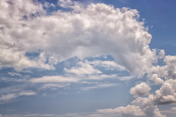 Blue sky and textured semicircular cloud in the center of the frame against the blue sky, semicircular clouds against the blue sky, clouds of unusual shape on a sunny day.