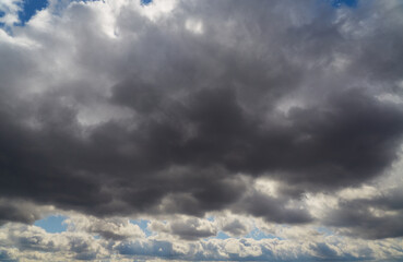 A large gray shelf cloud in the sky, close-up, background of clouds, sunlight breaks through and...