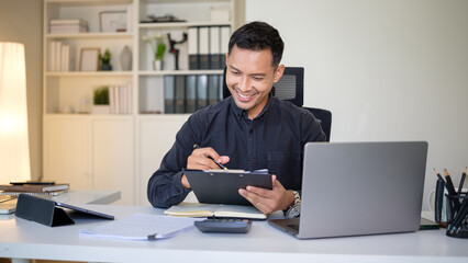 Smiling businessman reviewing financial documents at his desk in a bright and modern office.