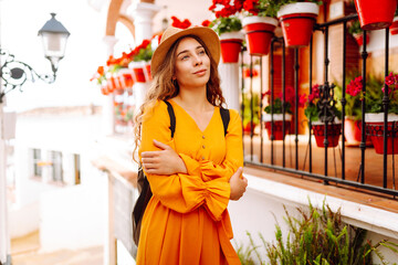 Beautiful tourist in bright dress enjoying trip to new city posing against white houses. Young...