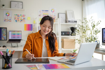 Smiling young woman drawing on a digital tablet. Happy and focused designer working in a colorful and creative office environment.