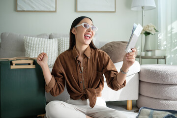 Excited young woman showing her passport and ticket while preparing for a trip. Sitting next to luggage and expressing joyful travel anticipation.