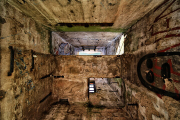 Abandoned concrete interior with graffiti and ceiling opening showing blue sky and light