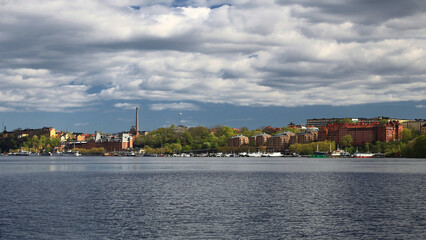 Stockholm waterfront skyline under dramatic clouds viewed across calm water in spring