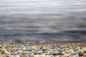 Pebbled shoreline meets still water in long exposure photography
