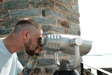 A man observing the Danube from Ram Fortress through a public binocular viewer. A popular tourist destination in Serbia country.