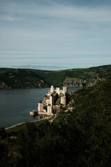 Elevated view of Golubac Fortress on the Danube, surrounded by lush green hills and blue sky. A popular tourist destination