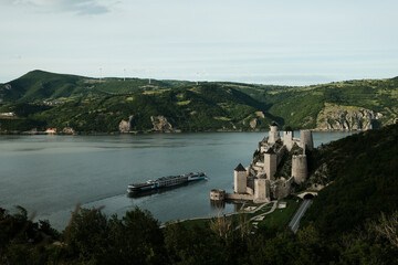 Panoramic scene of Golubac Fortress and Danube River with a cruise ship passing by. A popular tourist destination in Serbia