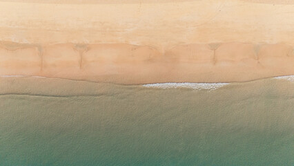 Bird's eye top aerial view of woman relaxing in sandy beach in the pristine turquoise shoreline and sweeping coastal landscape of Nacpan Beach in El Nido, Palawan, Philippines