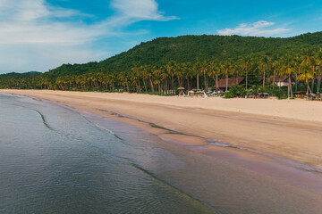 Stunning aerial view of Nacpan Beach’s winding shore, vibrant tropical greenery, and sparkling clear sea in El Nido, Palawan, Philippines