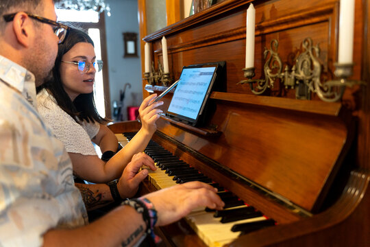 Musicians playing piano and reading music sheet on tablet
