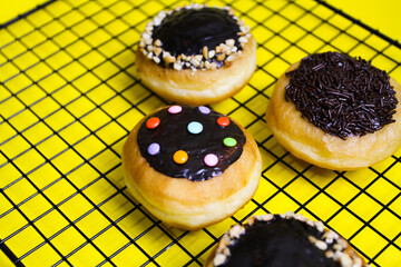 closeup row of sweet donuts with various flavors neatly arranged isolated on yellow background