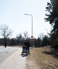 a serene suburban scene with a person walking a stroller on a sunlit sidewalk, flanked by trees and...