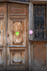 weathered carved wooden double door with ornate wrought-iron side window panel sports bright green...