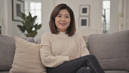 Obraz premium A cheerful woman enjoying a moment in her living room, seated on a cozy couch.