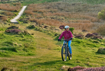 active senior woman riding her electric mountain bike at Mull of Galloway,  the southern most point...
