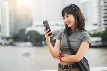 Young southeast asian woman happy teenager blogger using smartphone searching travel guide. World...