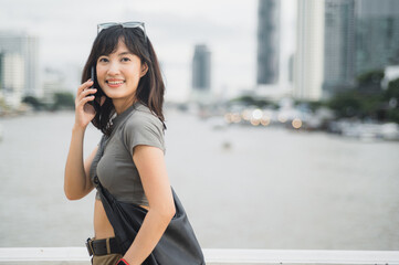 Obraz premium Happy solo Southeast Asian woman teenager blogger world travel tourism concept. Local cultural experience for explorer Bangkok Thailand. Wait for friend express joy by boat Chao Phraya River Asia