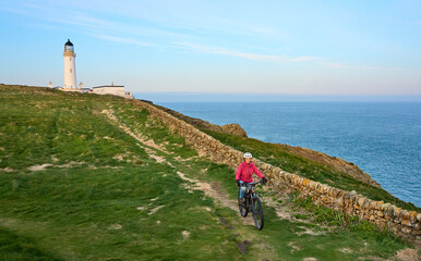 active senior woman riding her electric mountain bike at Mull of Galloway  lighthouse the southern...