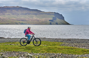active senior woman riding her electric mountain bike between blooming gorse in the wetlands of the...