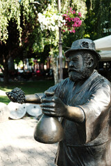 Bronze statue of a man offering grapes and a bottle, located in a park in town Vrsac, Serbia.
