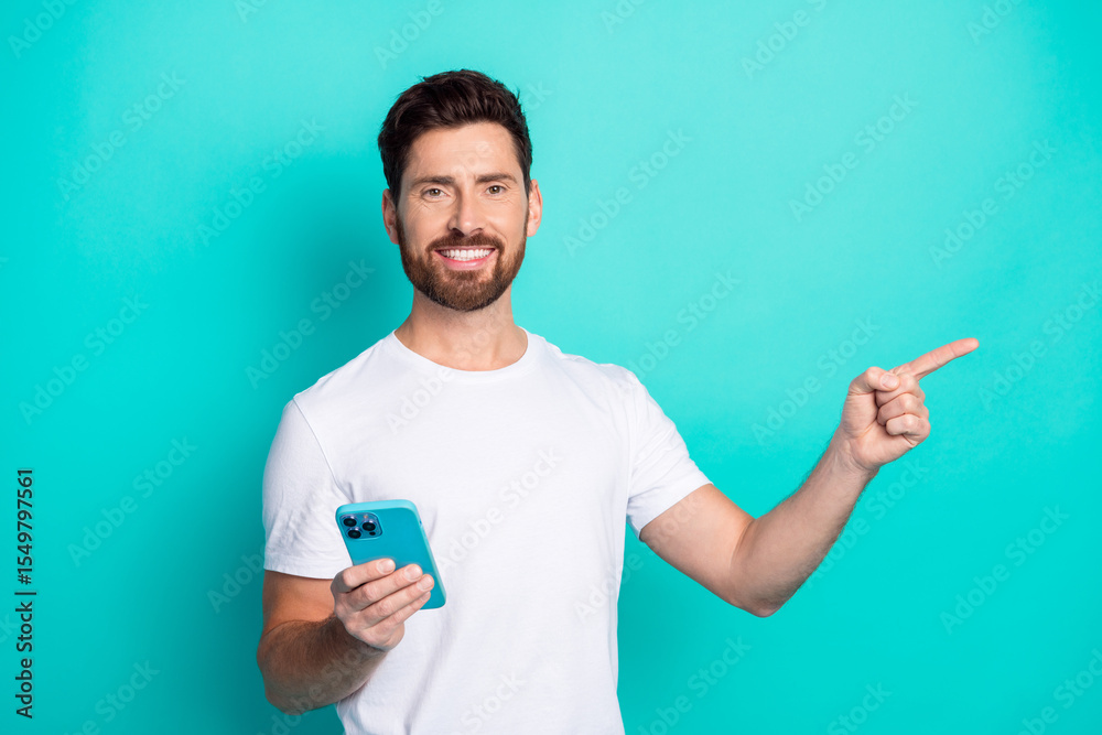 Poster happy man holding a smartphone while pointing at something exciting, promoting a concept or service 