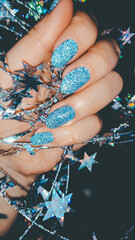 Hand with blue glitter nails holding shiny decorative stars