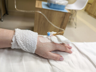 Hand with IV catheter, medical treatment, hospital bed, close-up view