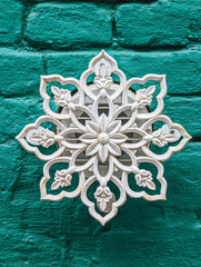 Decorative white wall piece mounted on textured green brick surface