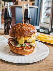 Delicious gourmet burger with lettuce, cheese, sauce, and side fries on a plate.