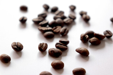 Naklejka premium Roasted coffee beans are scattered on the table. White background.