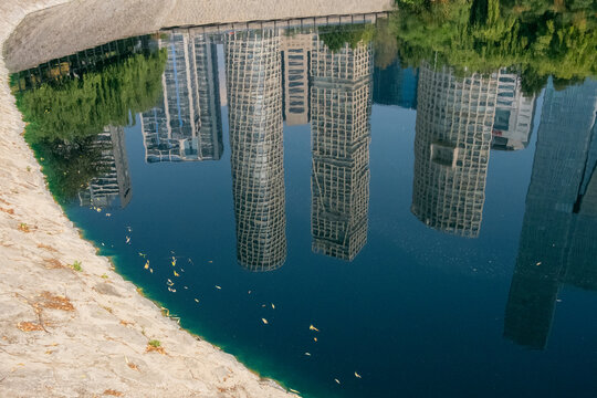 Minimalist architectural reflection of Santa Fe's skyline in the curved water canal of La Mexicana Park, Mexico City, highlighting urban growth and design symmetry