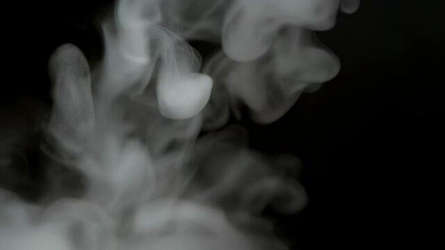 Ethereal smoke swirls gracefully against a dark background in slow motion