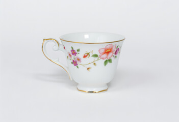Elegant porcelain teacup with delicate floral design, vintage style on a neutral background.