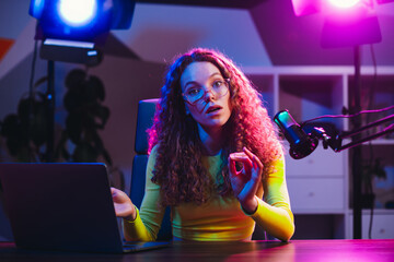 Popular blogger streamer with curly hair engaging in live online interactions using modern...