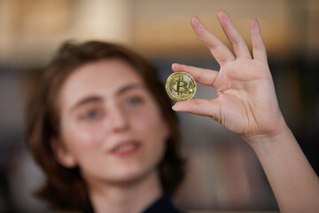 close up businesswoman holding and showing golden bitcoin cryptocurrency on hand
