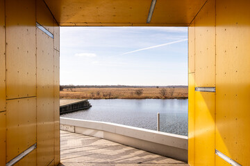 Bright yellow corridor framing a view of the water, highlighting symmetry, contrast and spatial framing in contemporary architecture