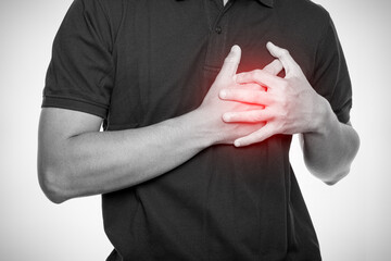  Man holding chest with both hands in pain, red glow highlighting the area, symbolizing heart...