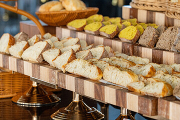 Creative display of various types of bread artfully arranged on a buffet table in a restaurant. A visually appealing assortment perfect for catering, brunches, or gourmet food presentations
