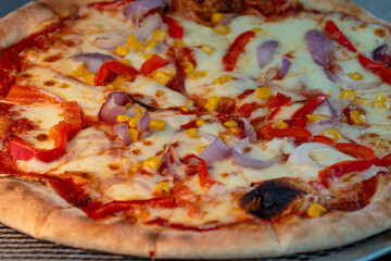 Close-up photo of a freshly baked pizza topped with onion slices, cherry tomatoes, corn, and melted cheese. The colorful and appetizing combination is perfect for vegetarian meals, fast food, or comfo
