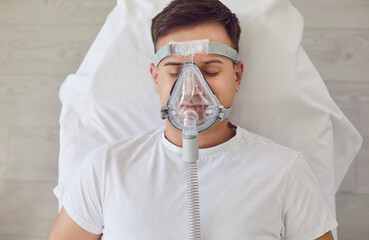 Front view portrait of Caucasian man lying in hospital bed with oxygen mask. Ventilation, sick...
