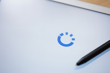 A blue circular loading icon is displayed on a tablet screen